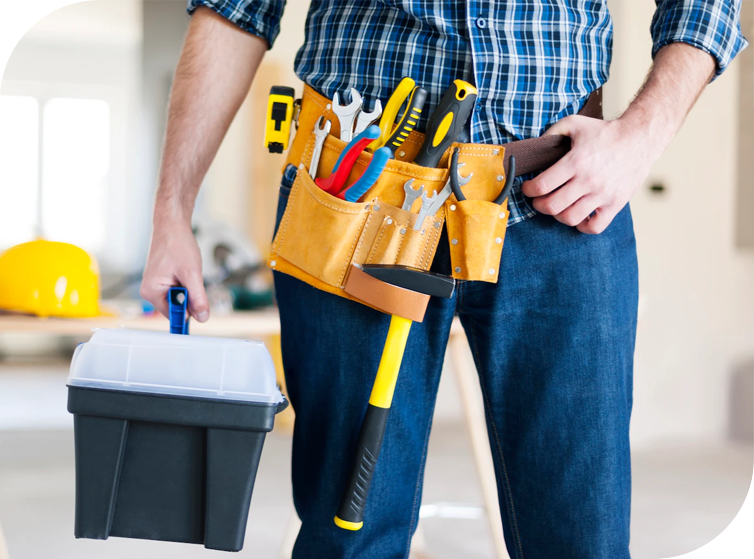 Handyman wearing tool belt with various tools and holding a toolbox.